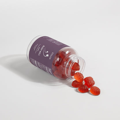 Tilted bottle of Sleep Well melatonin gummies spilling gummies onto surface