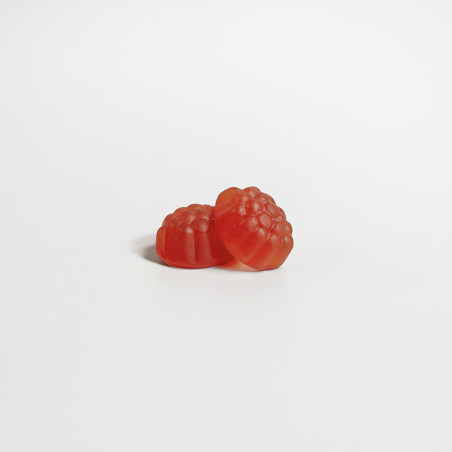 two melatonin gummies spilled on white background